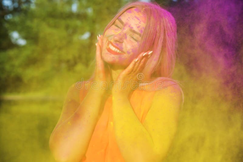 Closeup portrait of cheerful young woman having fun in a cloud of yellow dry Holi paint. Closeup portrait of cheerful blonde girl having fun in a cloud of yellow stock image